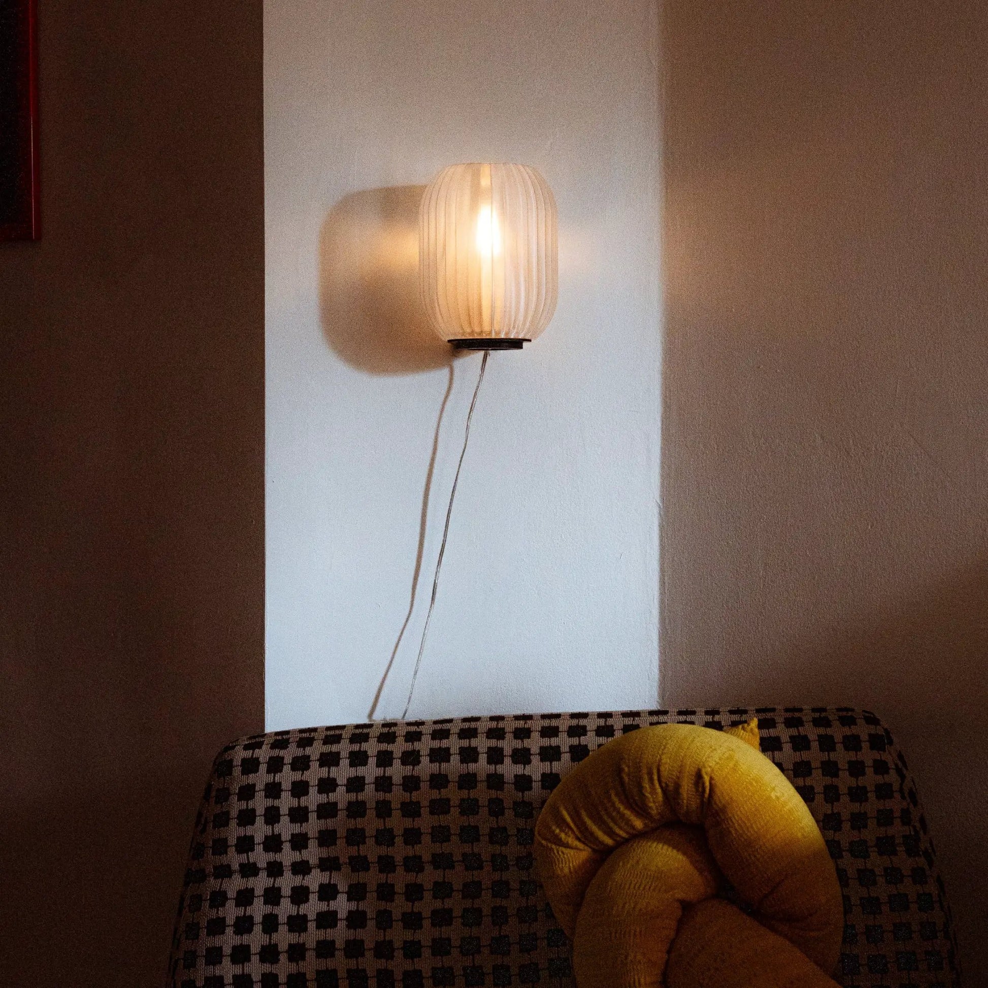 Allium Sconce wall light with cream pleated shade emits warm glow on wall on Tampa Home & Garden Store