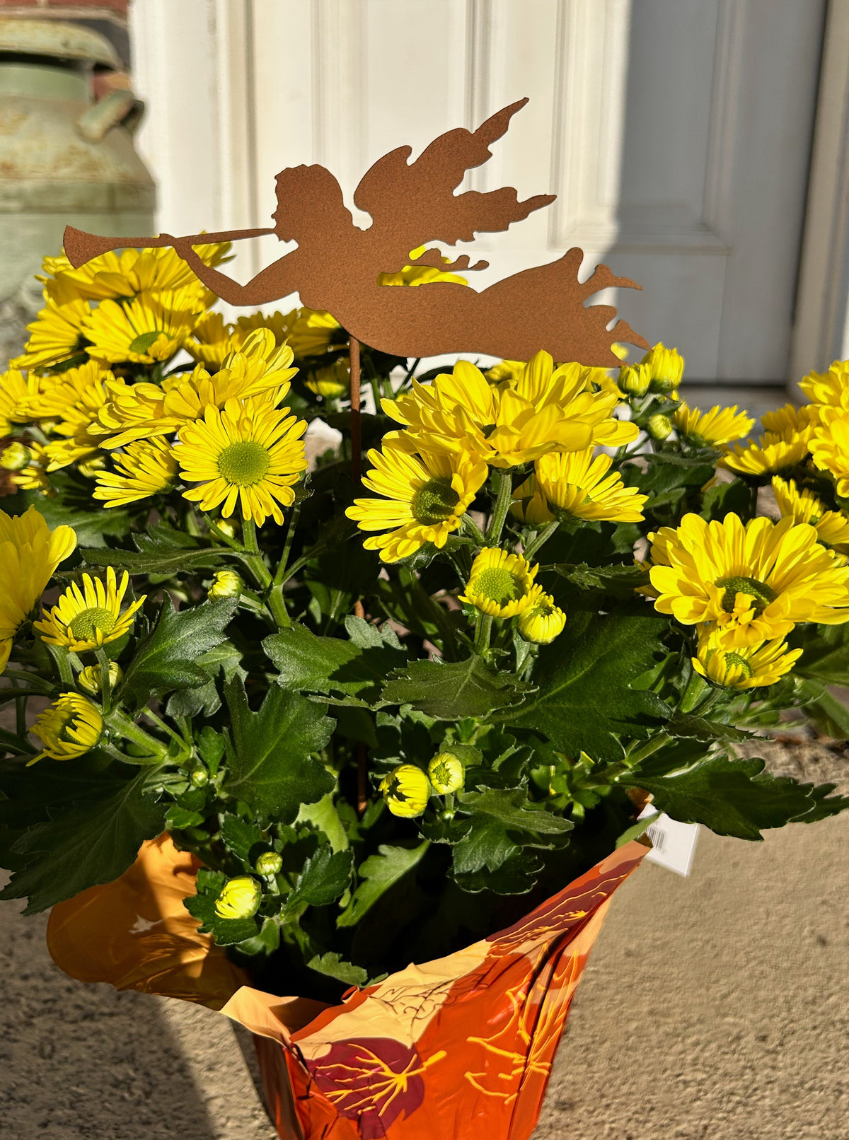 Angel plant stake rust-colored metal by Rustica Ornamentals in a yellow chrysanthemum pot on Tampa Home & Garden Store