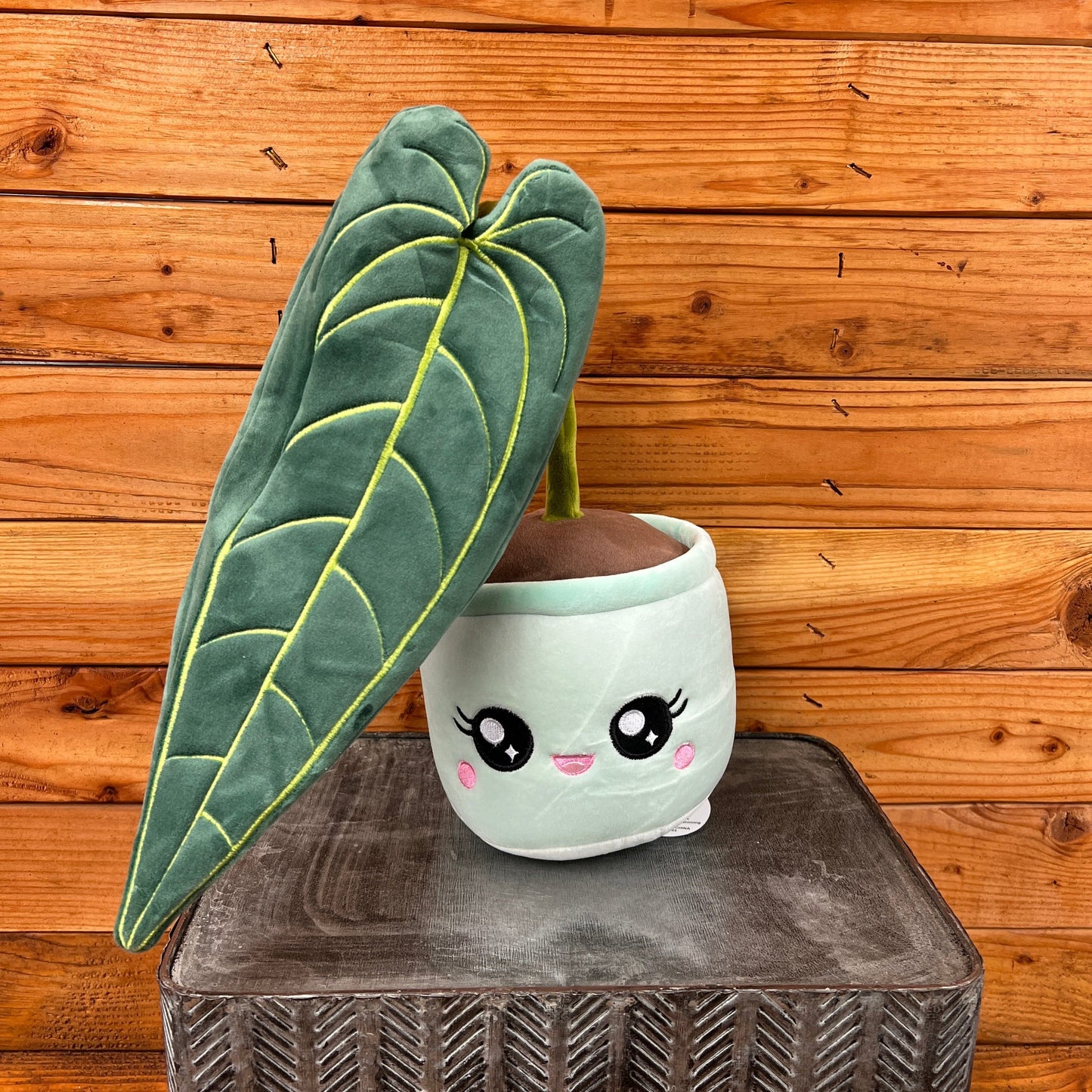 Cute plush plant with a pot against a wooden background