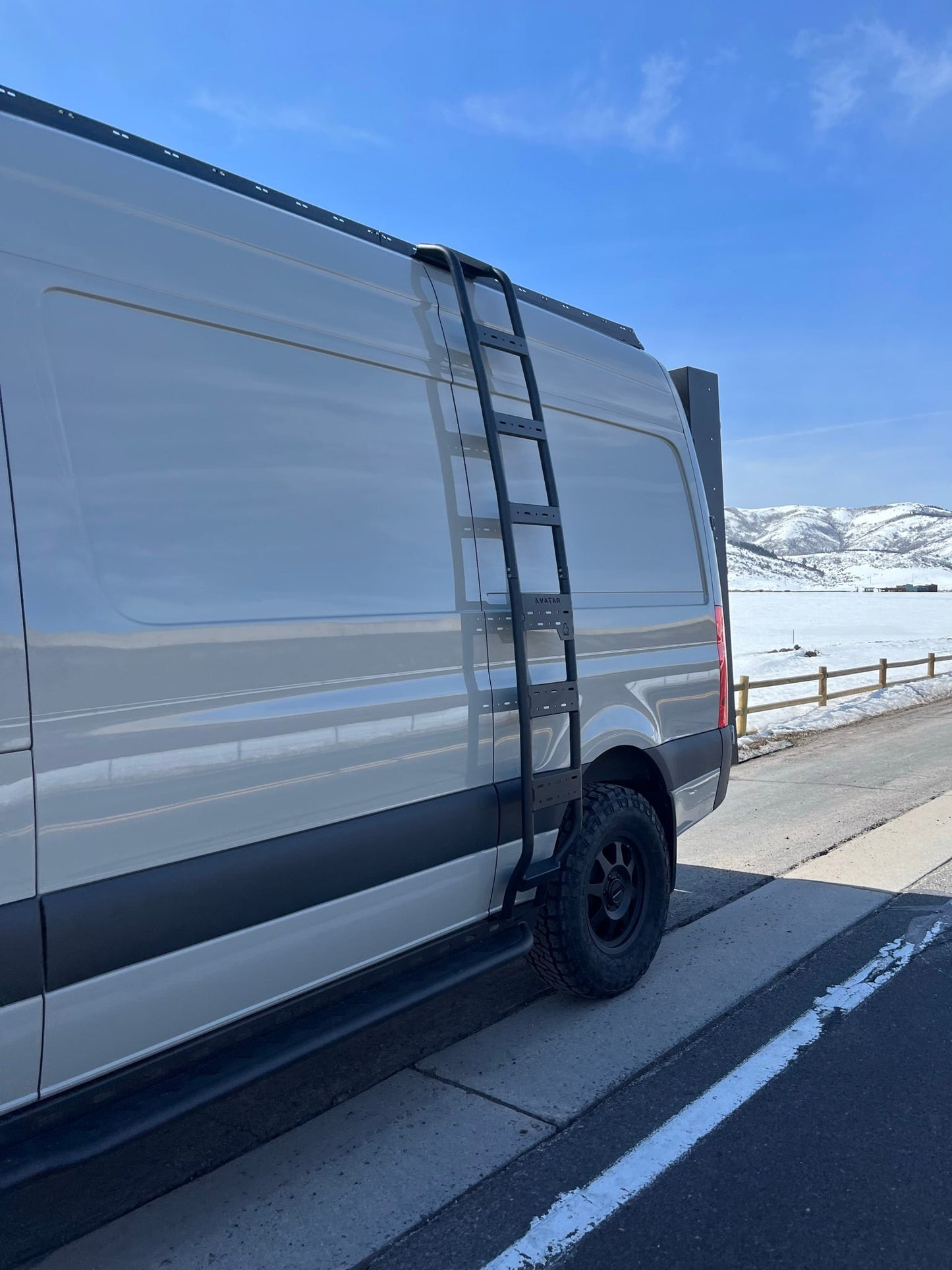 The Ultra Rack by avatar offroad low-profile roof rack on a Sprinter van with a black side ladder on Tampa Home & Garden Store