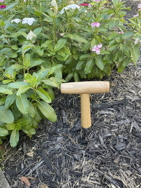 Steel dibber planting tool by Garden Guru with wooden handle beside a shrub in mulch on Tampa Home & Garden Store