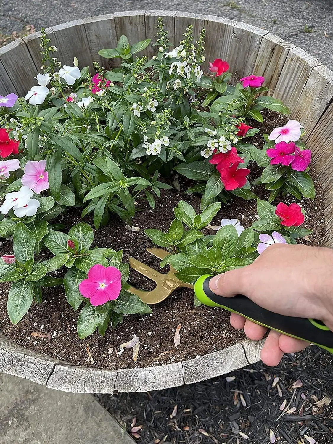 Garden Guru titanium hand weeder fork with green and black handle in a wooden planter bed on Tampa Home & Garden Store