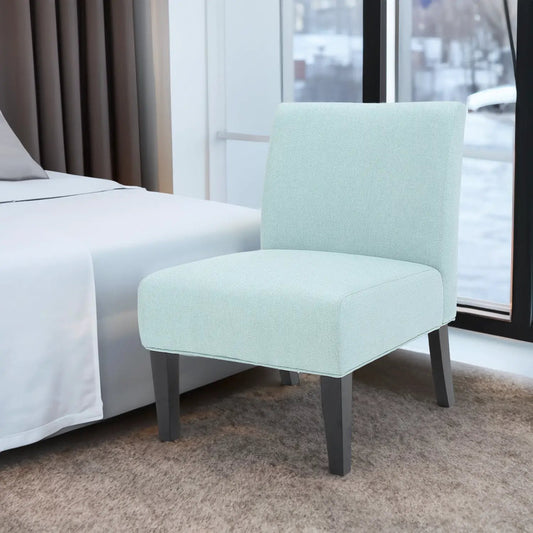 Light blue fabric accent chair with dark tapered legs beside a bed by a window on Tampa Home & Garden Store