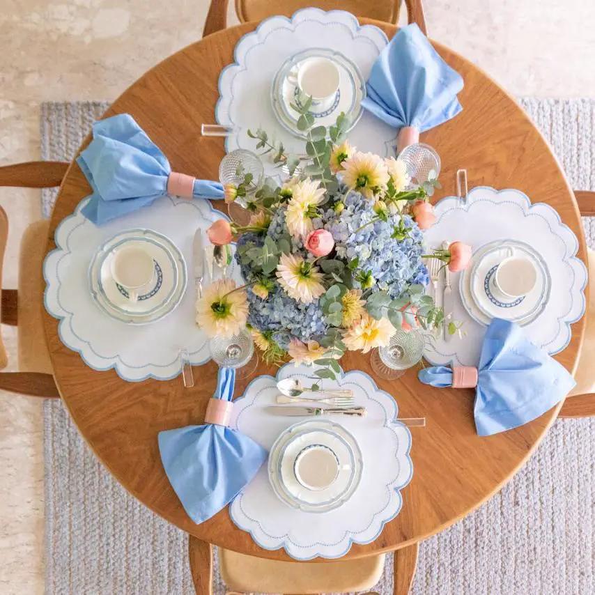 Solid blue cotton napkins by Talah Home set for five on placemats with a floral centerpiece on Tampa Home & Garden Store