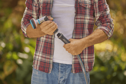 Gardena 30m garden hose X-Flow (5/8) with blue nozzle, held by a person in a plaid shirt on Tampa Home & Garden Store