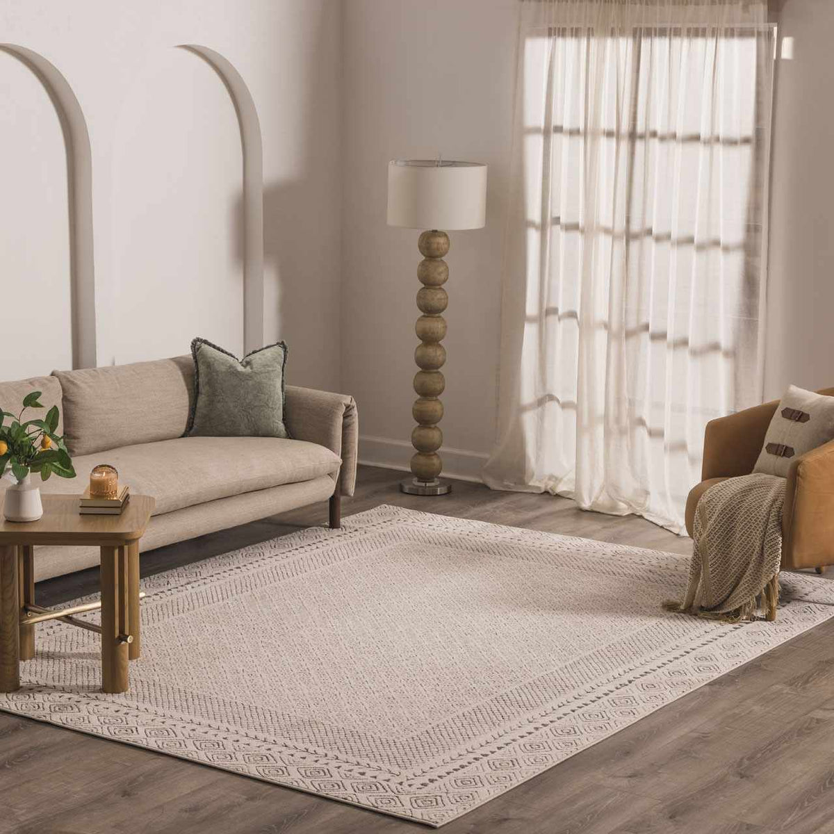 Burdette Soft Neutral Rug in cream beige with a subtle border in a modern living room on Tampa Home & Garden Store