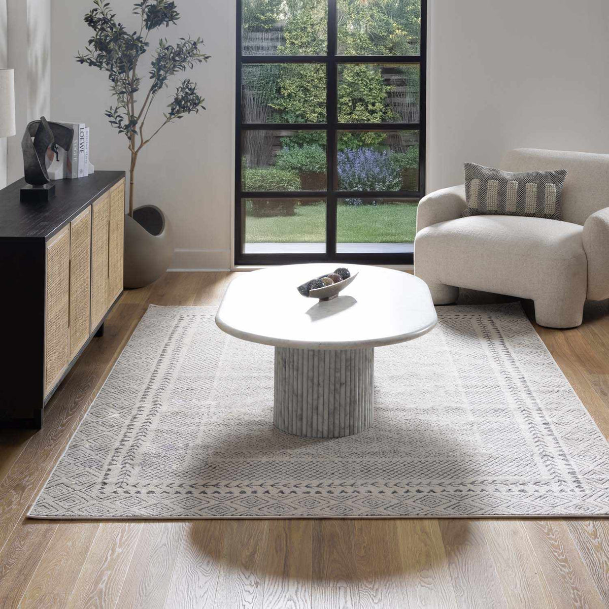 Burdette Soft Neutral Rug by Boutique Rugs in gray with subtle border in living room on Tampa Home & Garden Store