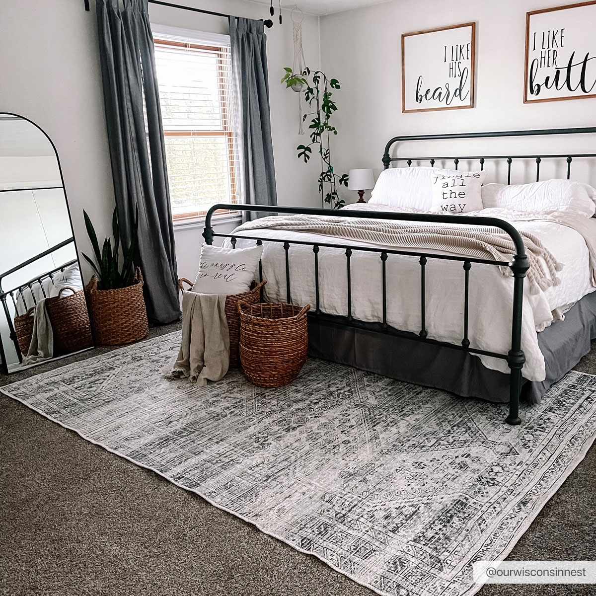 Barny Sage Flat Pile Washable Rug by Boutique Rugs under a black metal bed in a cozy bedroom on Tampa Home & Garden Store