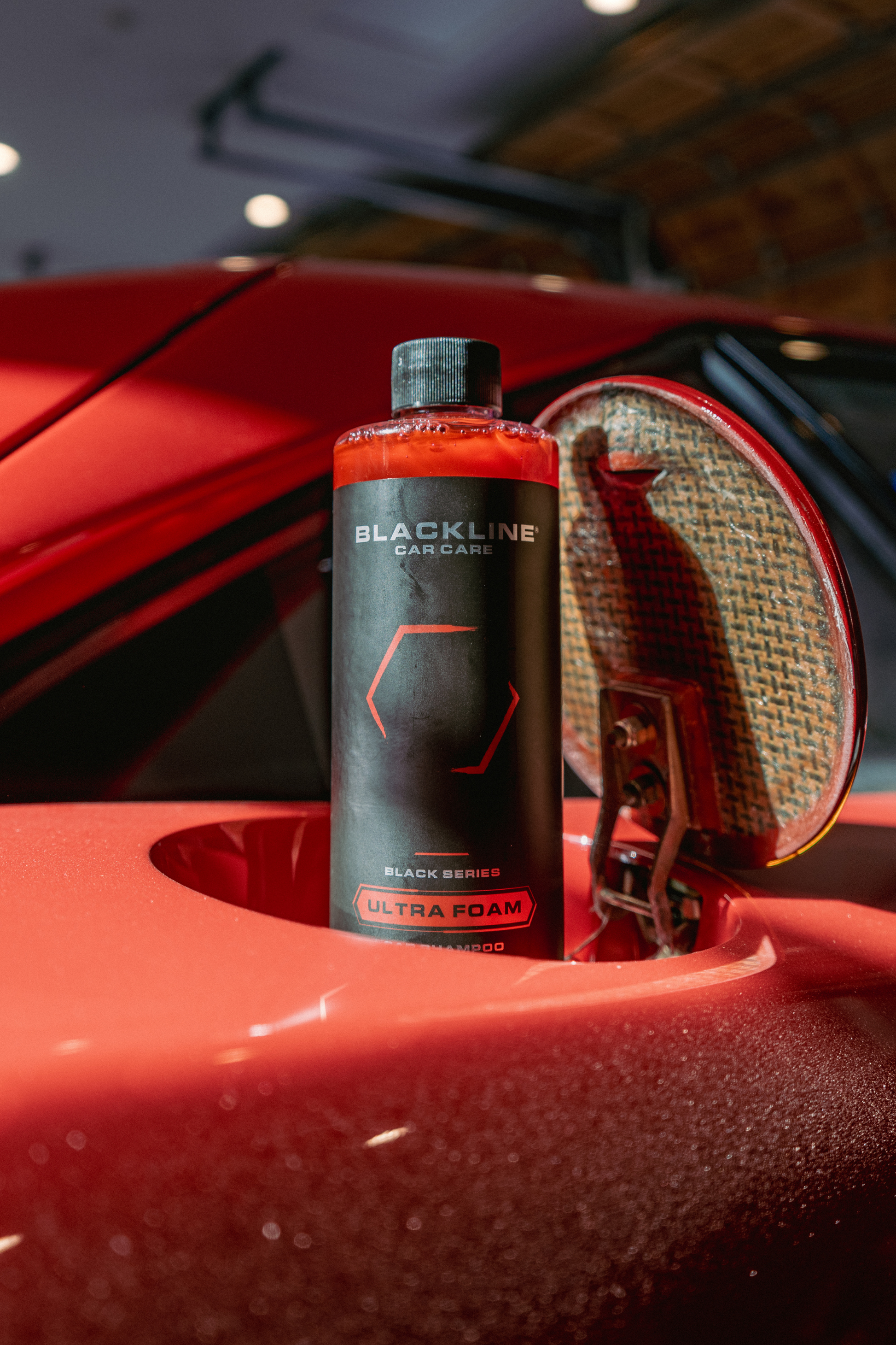 Blackline Car Care Ultra Foam car shampoo bottle with black label beside red car wheel on Tampa Home & Garden Store