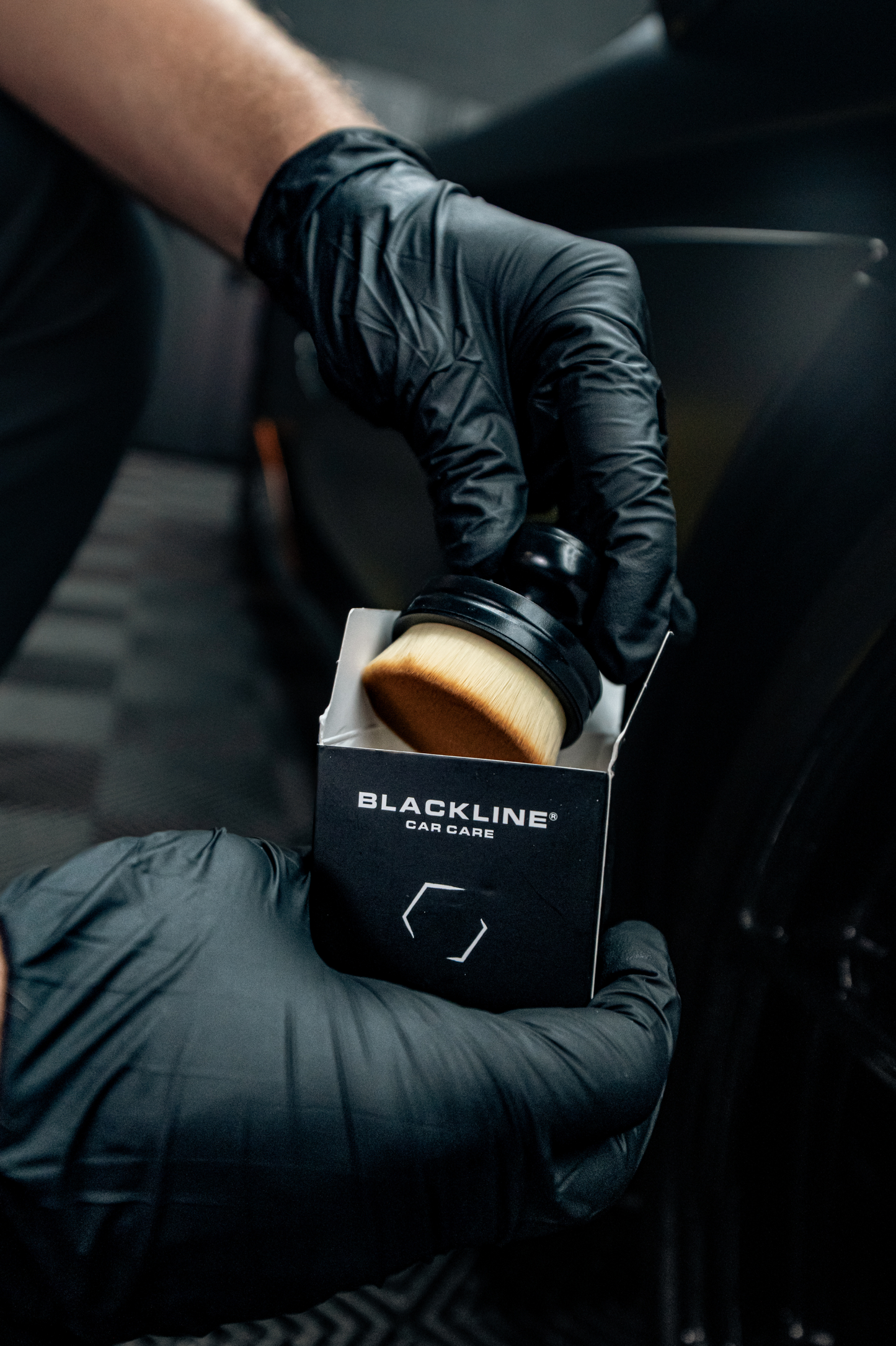 BLACKLINE Tire Shine Applicator Brush held by gloved hand with Blackline Car Care packaging on Tampa Home & Garden Store