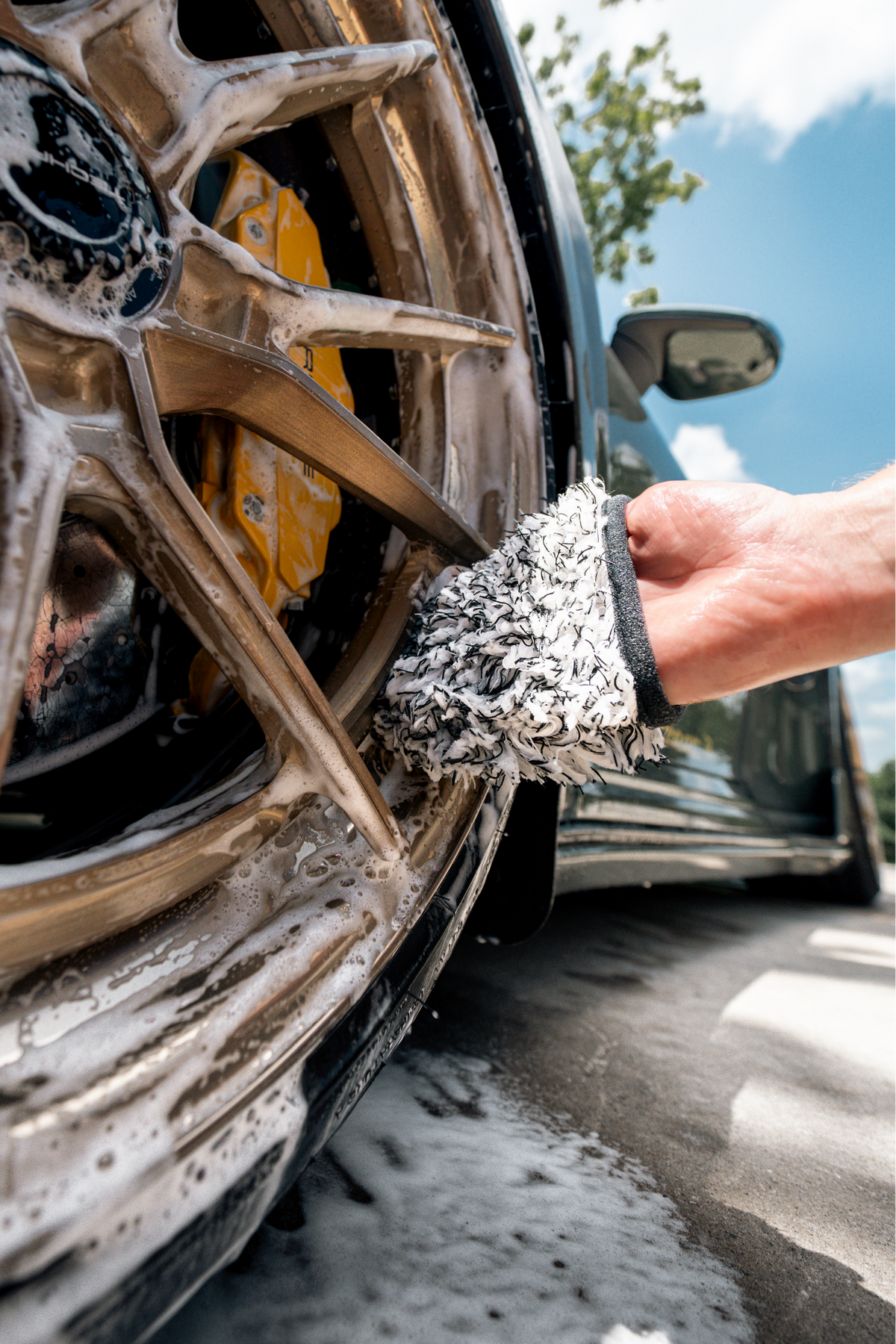 BLACKLINE® MICROFIBER WHEEL MITT gray microfiber scrubs a soapy car wheel with yellow brake caliper on Tampa Home & Garden Store