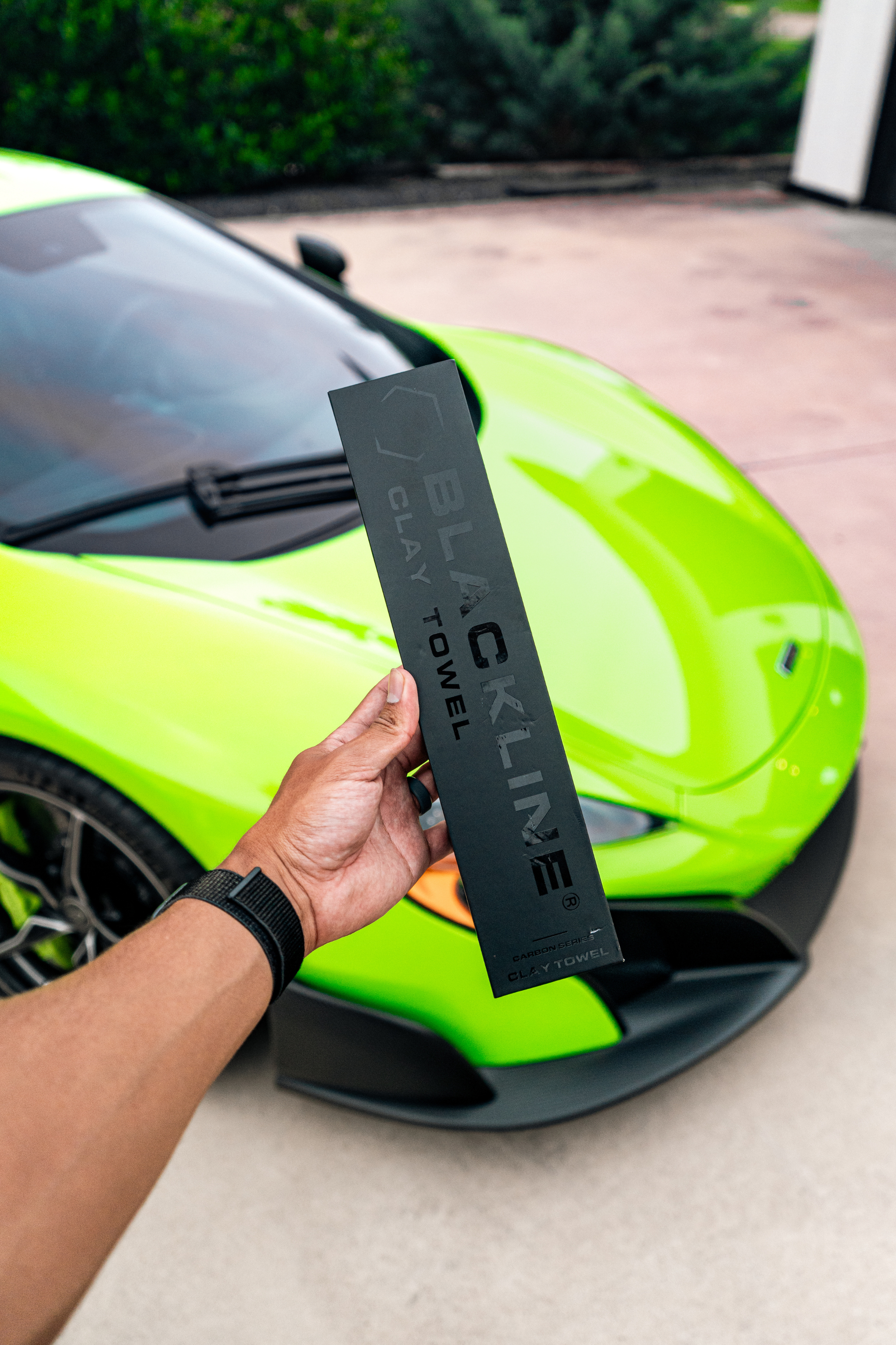 Blackline Synthetic Clay Towel packaging held in front of a lime green sports car on Tampa Home & Garden Store