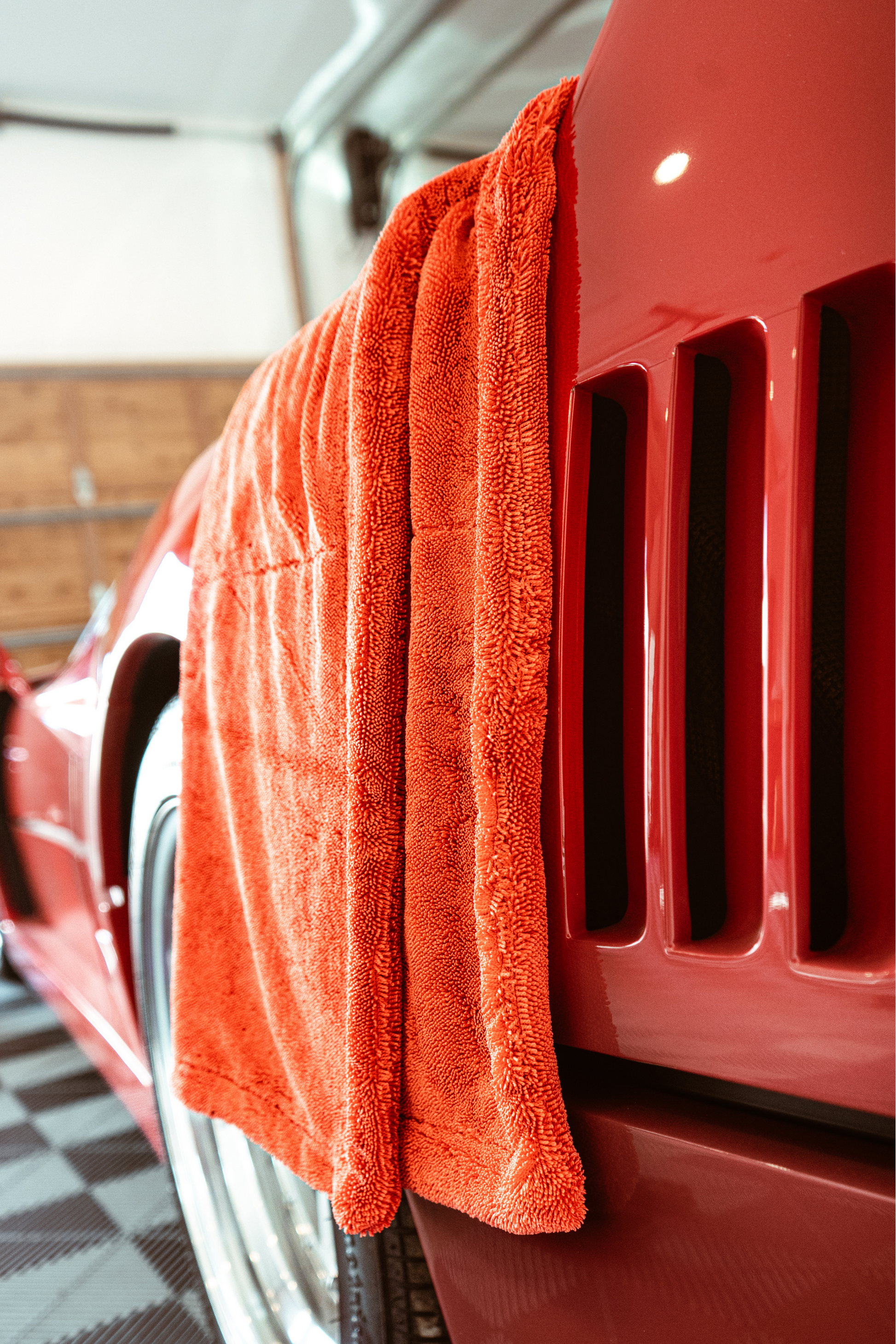 BLACKLINE Twisted-Loop Drying Towel orange hanging on a red car door panel in a garage on Tampa Home & Garden Store