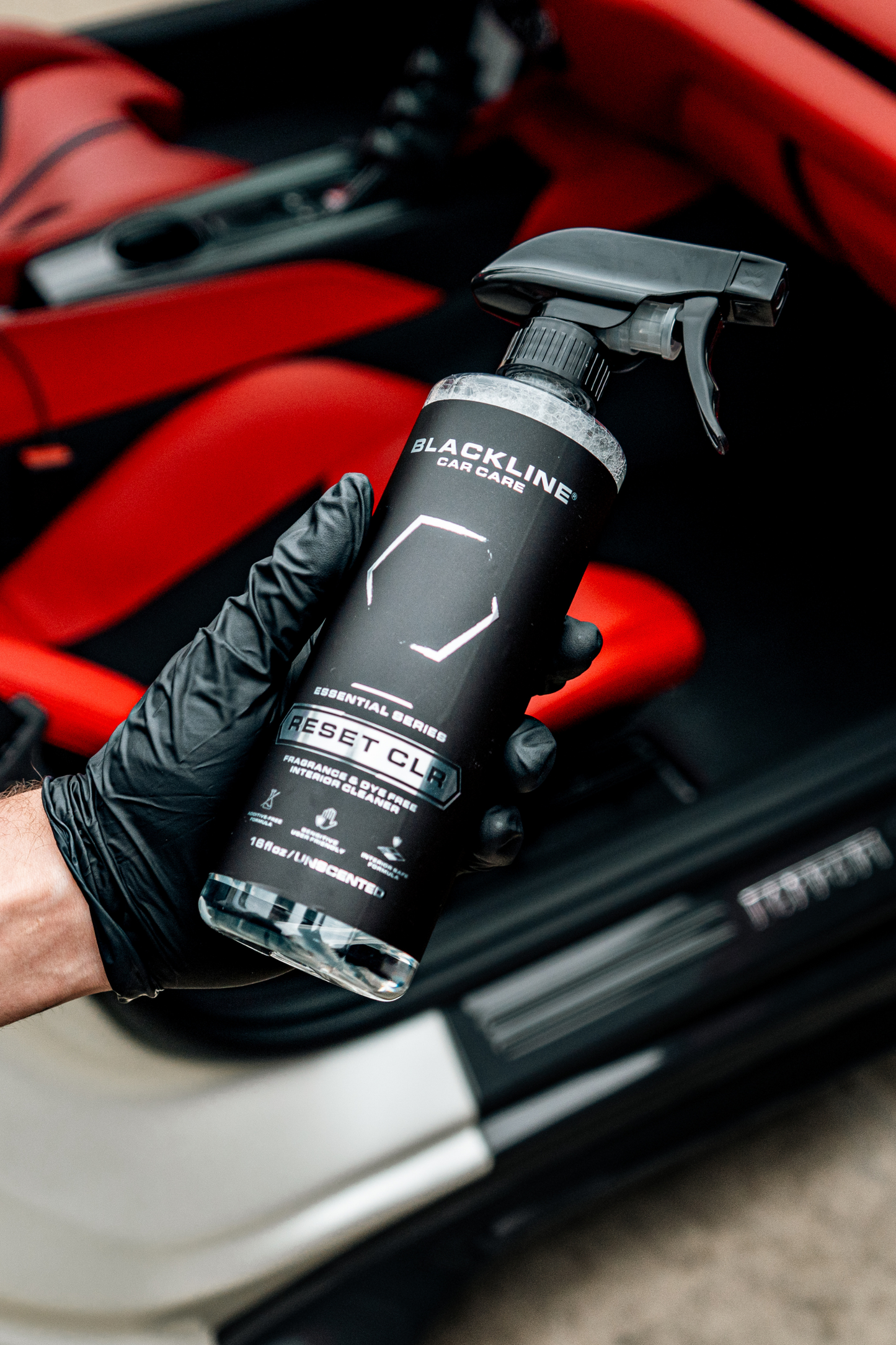 Blackline Car Care Reset Interior Cleaner spray bottle in gloved hand with red backdrop on Tampa Home & Garden Store