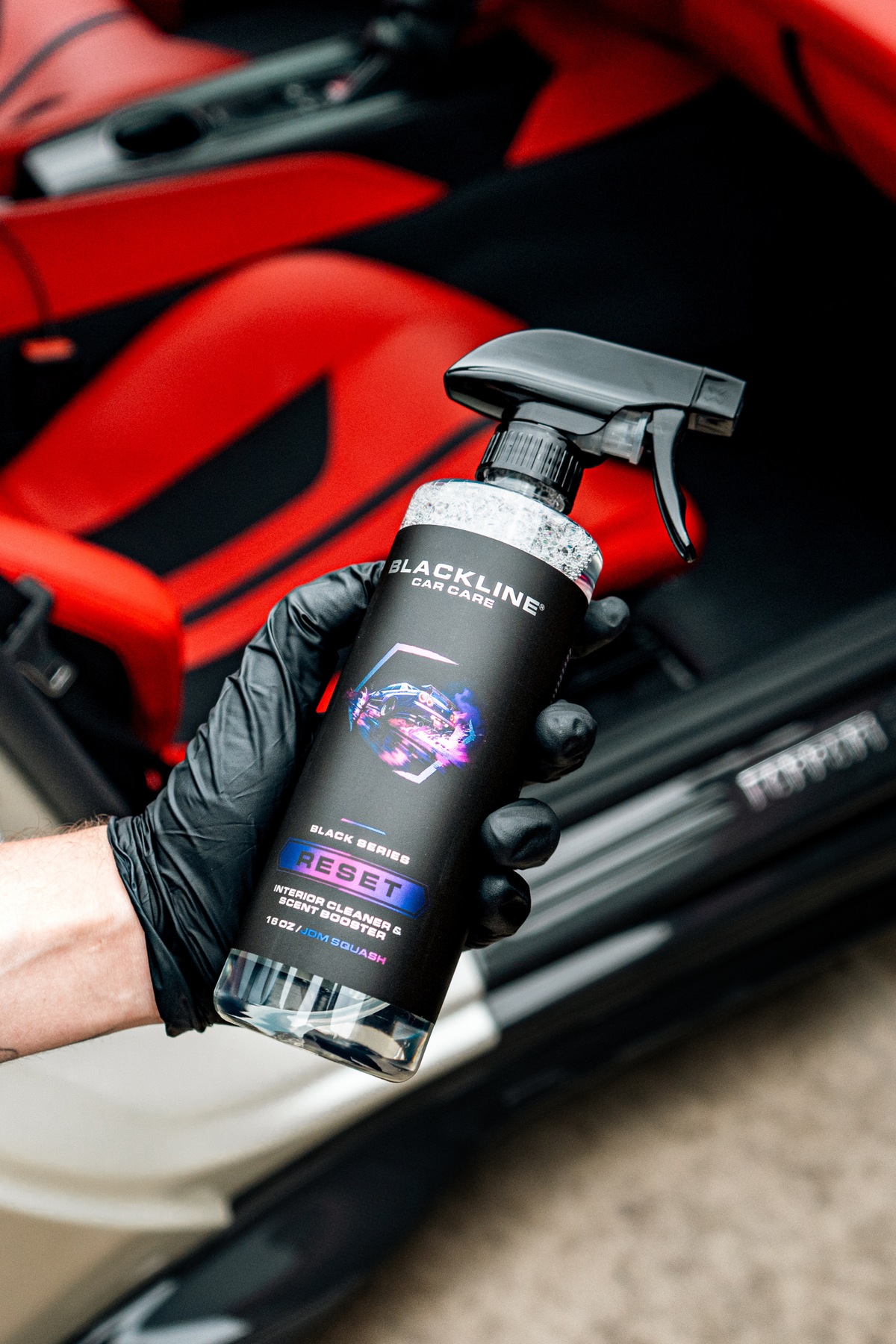 Blackline Car Care RESET interior cleaner spray bottle in gloved hand, red car interior on Tampa Home & Garden Store
