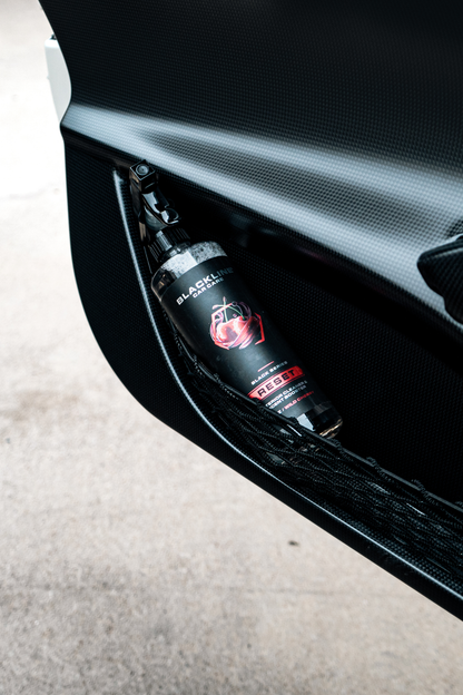 Blackline Car Care Reset interior cleaner spray bottle in door pocket against carbon fiber on Tampa Home & Garden Store