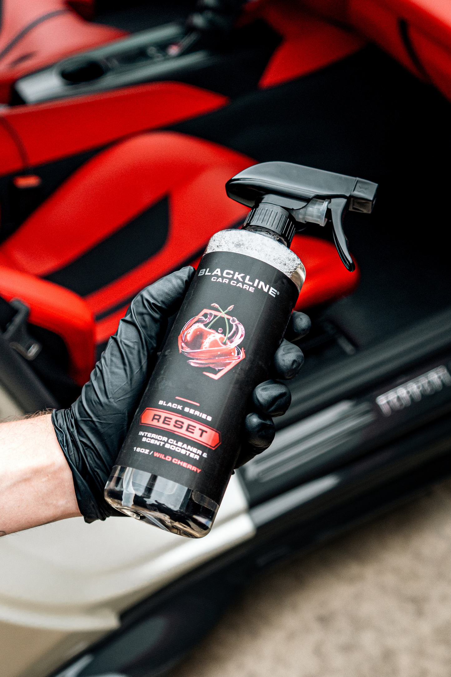 Blackline RESET interior cleaner spray bottle held by gloved hand inside a red car interior on Tampa Home & Garden Store