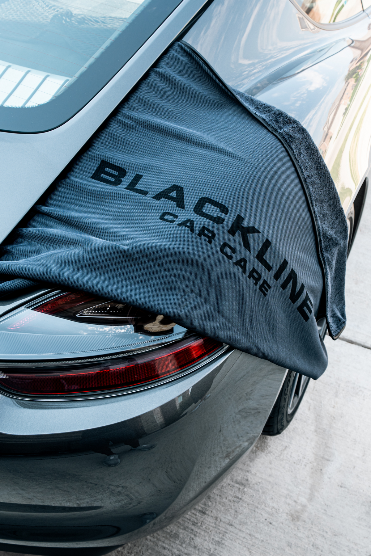 BLACKLINE Slim Twisted-Loop Drying Towel draped over car trunk, dark gray microfiber branding on Tampa Home & Garden Store