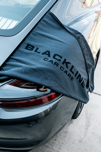 BLACKLINE Slim Twisted-Loop Drying Towel draped over car trunk, dark gray microfiber branding on Tampa Home & Garden Store