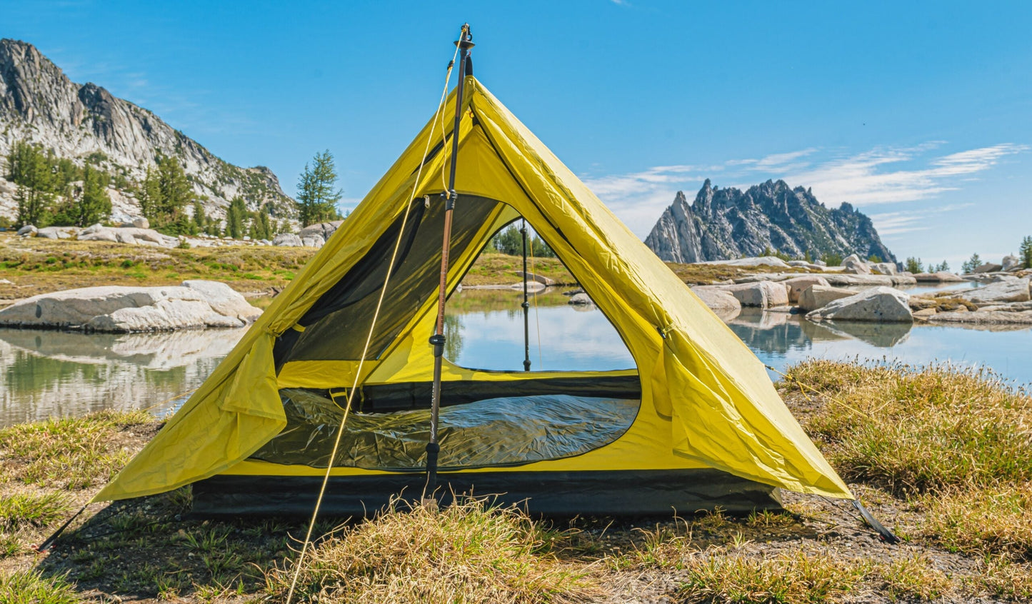Trekker Palace 2-Person Backpacking Tent in bright yellow pitched by a lake with mountains on Tampa Home & Garden Store
