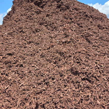 Bulk brown mulch for sale by the yard shown stacked in a big pile.