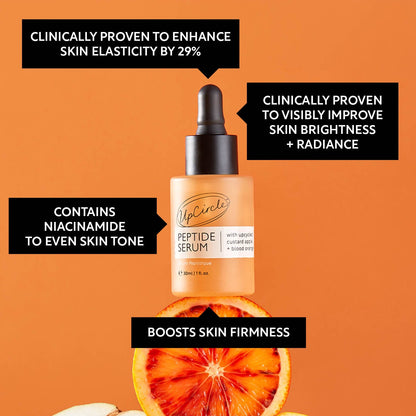 UpCircle peptide serum bottle in orange-tinted glass with black dropper, citrus slices backdrop on Tampa Home & Garden Store