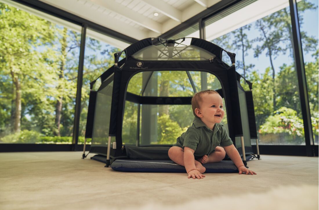Pop 'N Go Playpen play yard with black frame and mesh sides, baby on blue mat indoors on Tampa Home & Garden Store