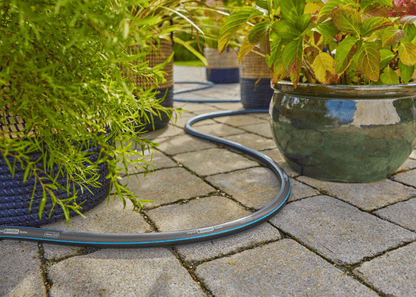 Gardena garden hose 30m 100ft 5/8 X-Flow coiled on stone patio beside potted plants on Tampa Home & Garden Store