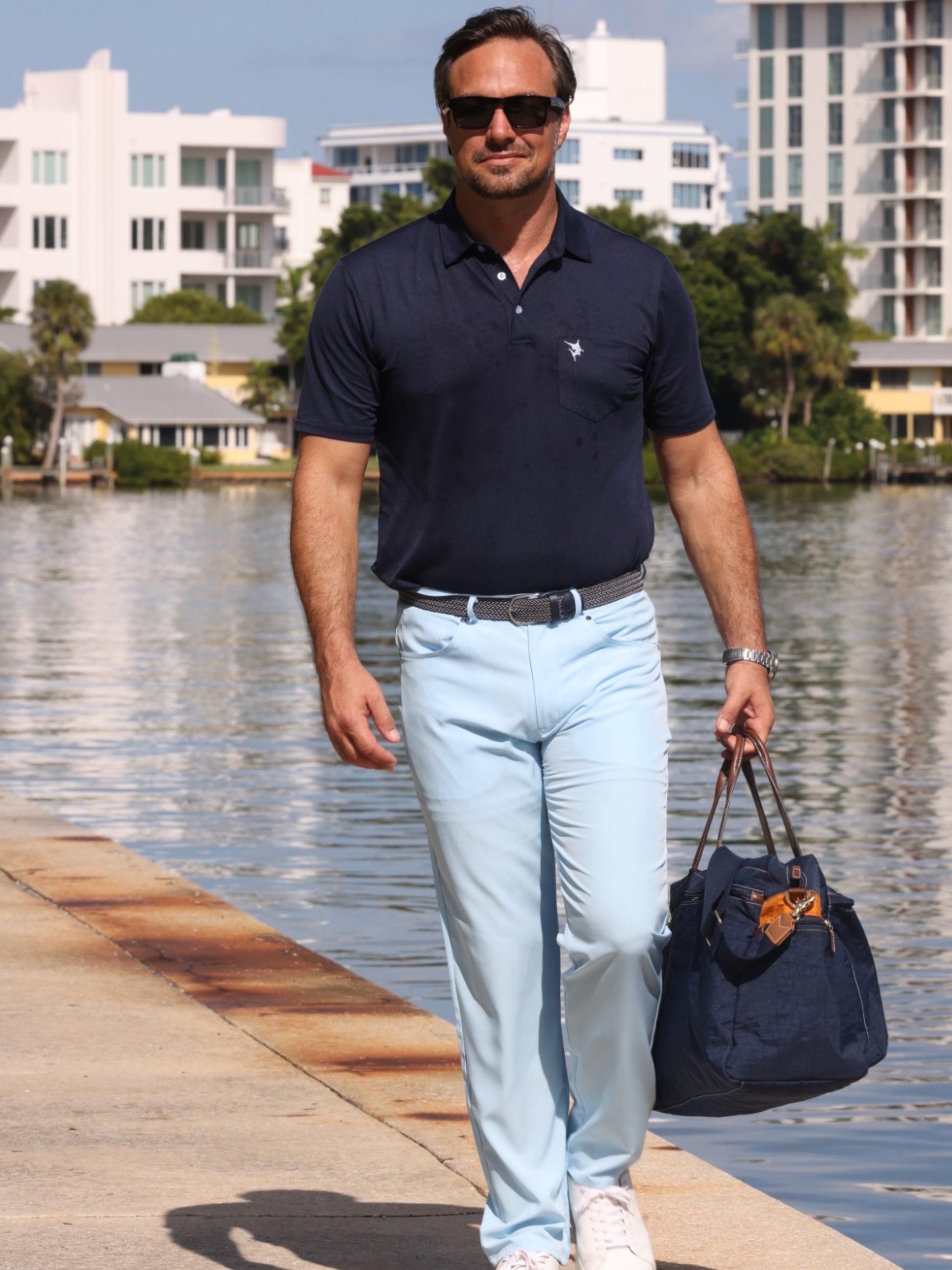 Charleston Polo by White Water Life navy polo on man beside water with light blue pants on Tampa Home & Garden Store
