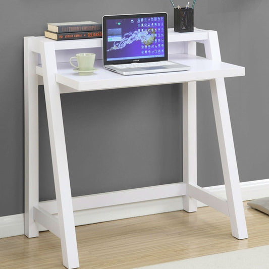 Small white desk with a laptop, mug, and books against a gray wall.