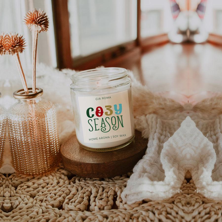 Cozy Season Candle by Gia Roma in a clear glass jar with white wax on a wooden coaster on Tampa Home & Garden Store