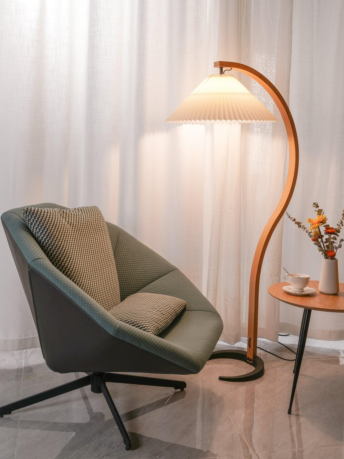 Arbora Arc floor lamp with beech wood arc and pleated shade, plug-in beside a table and chair on Tampa Home & Garden Store