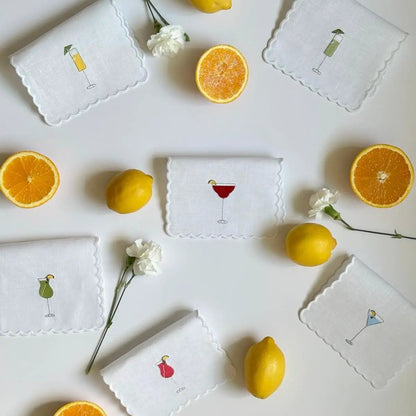 Six white linen cocktail napkins with scalloped edges and colorful embroidered drinks on Tampa Home & Garden Store