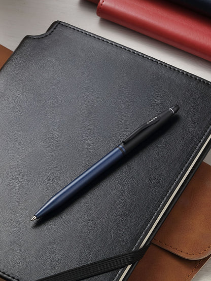 A.T. Cross Click Tuxedo Satin Metallic Blue ballpoint pen atop a black leather notebook on Tampa Home & Garden Store