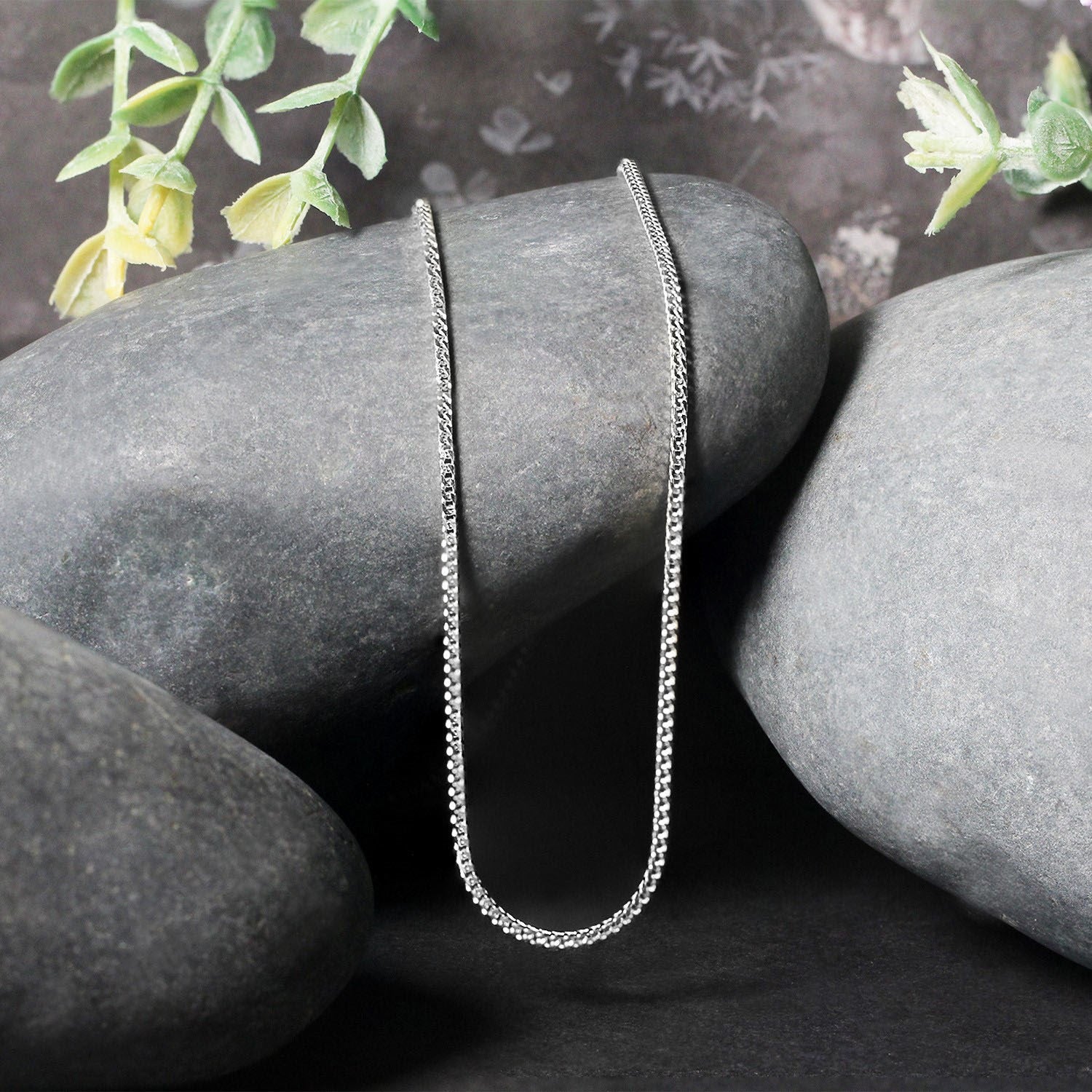 14k white gold Franco chain necklace 1.2mm draped over smooth gray stones on Tampa Home & Garden Store