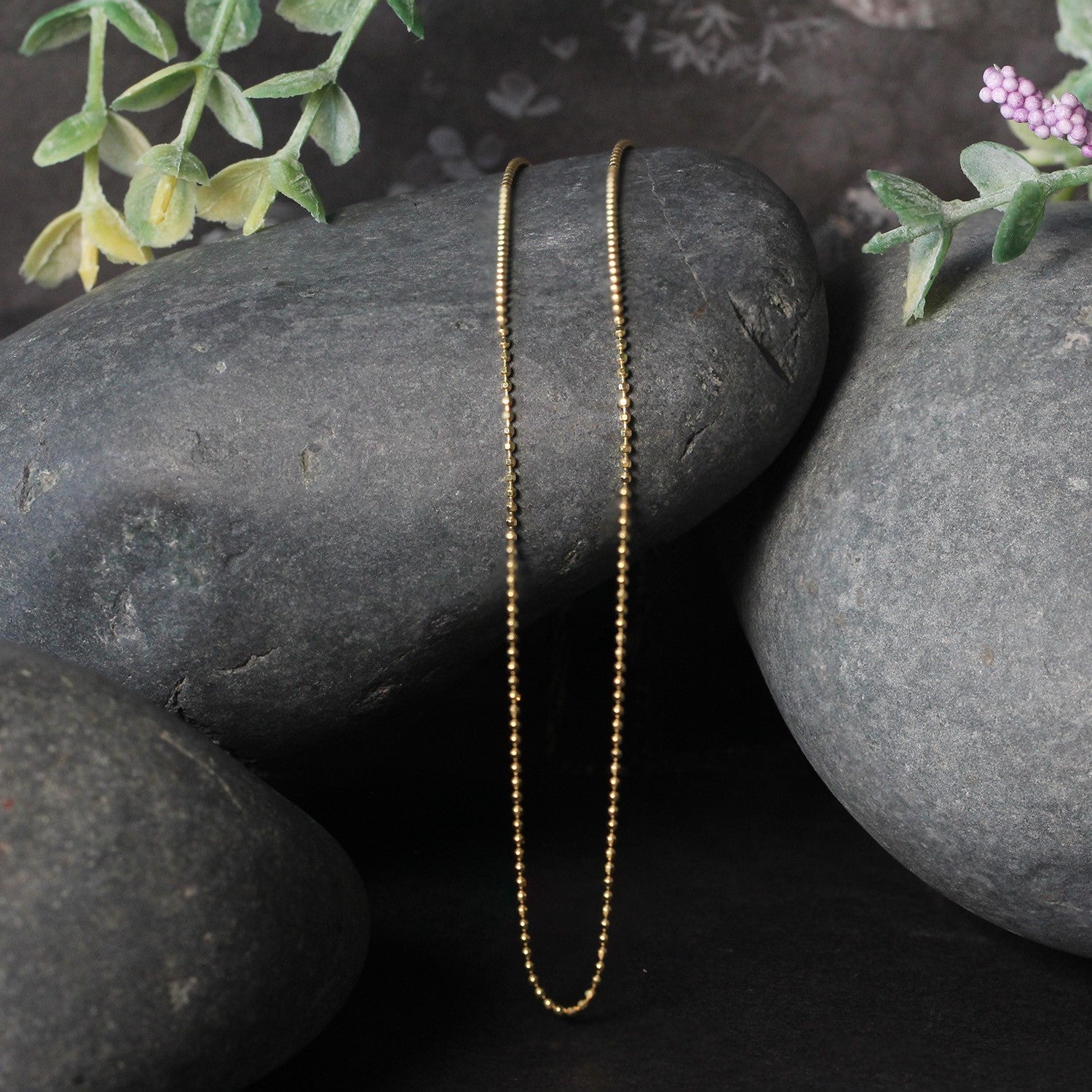14k yellow gold diamond-cut bead chain necklace 1.0mm Bids.com displayed on dark stones on Tampa Home & Garden Store