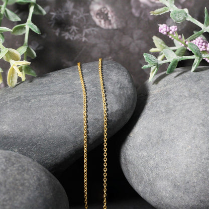 14k yellow gold Forsantina Lite cable link chain necklace 1.5mm draped over gray stones on Tampa Home & Garden Store
