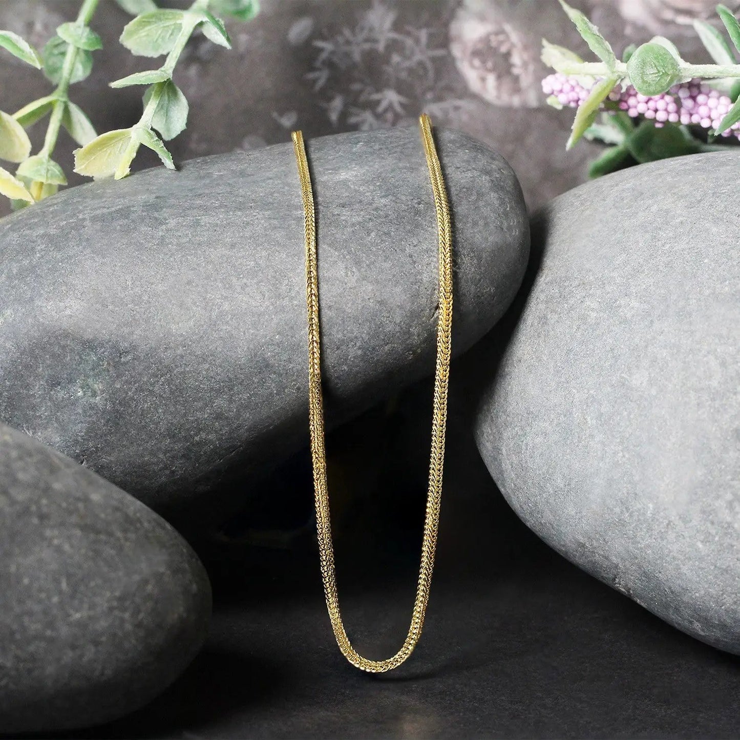 Two 1.0mm foxtail chain necklaces in 14k yellow gold by Bids.com resting on gray stones on Tampa Home & Garden Store