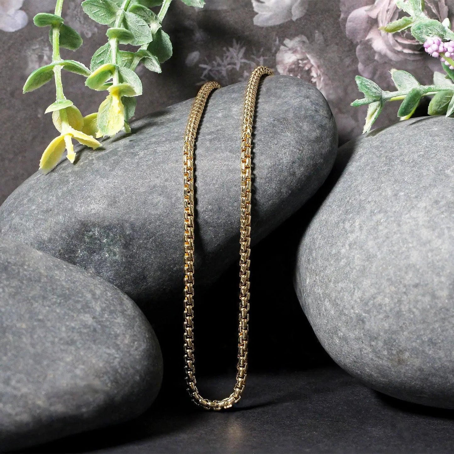 14k yellow gold solid box chain necklace 2.5 mm draped over gray stones with green plants on Tampa Home & Garden Store