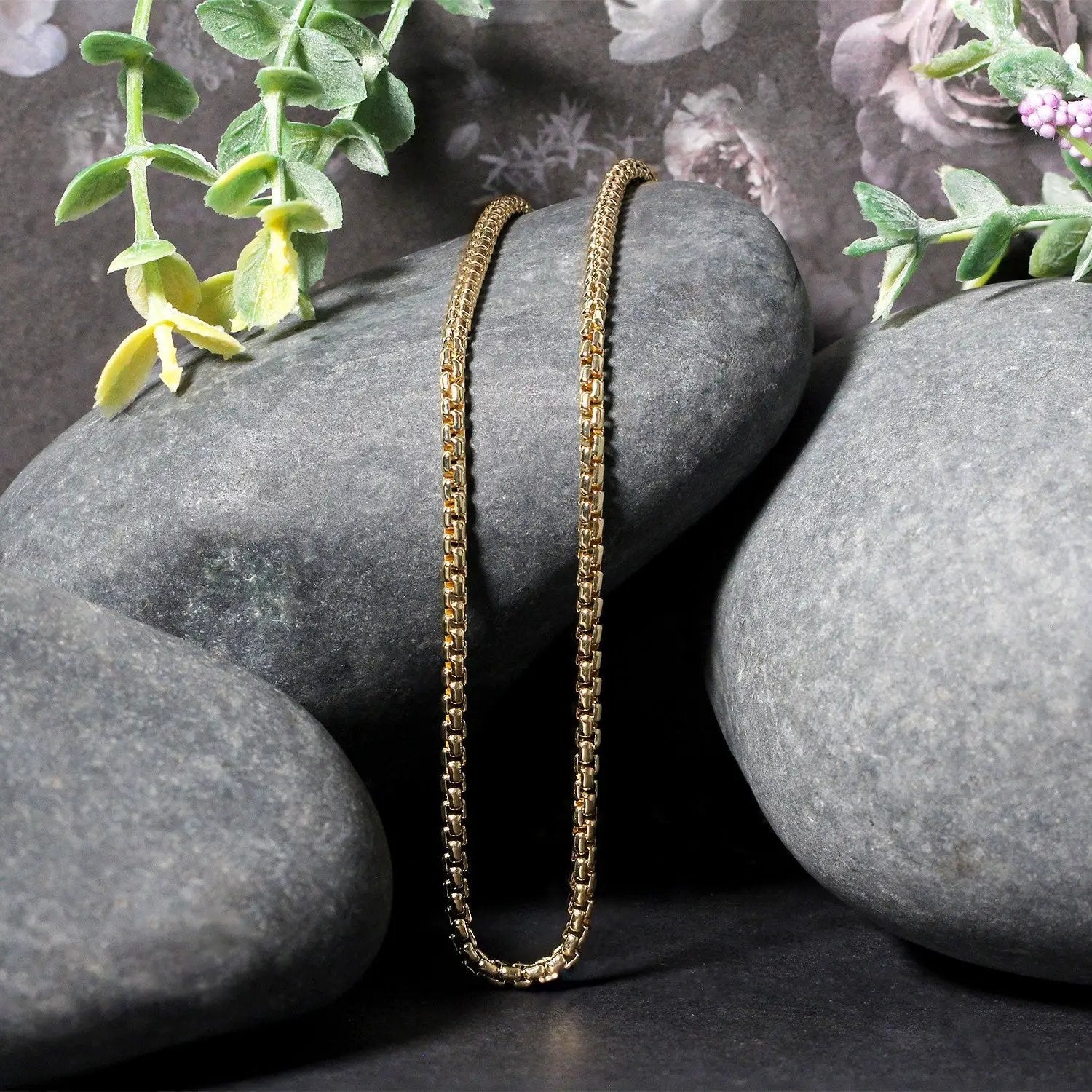 14k yellow gold solid box chain necklace 2.5 mm draped over gray stones with green plants on Tampa Home & Garden Store