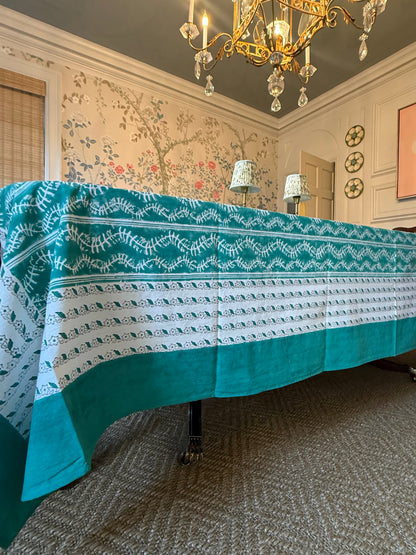 Bluebell Tablecloth in Emerald, teal border with white leaf pattern draped over a table on Tampa Home & Garden Store
