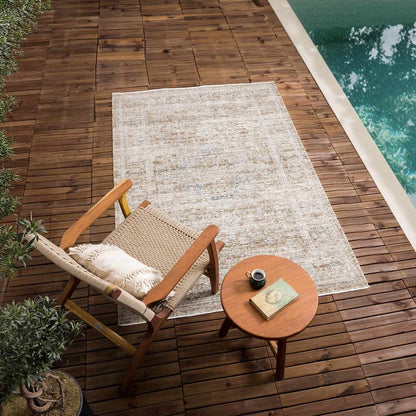 Aistys washable outdoor rug by Boutique Rugs, beige distressed pattern on a wooden poolside deck on Tampa Home & Garden Store