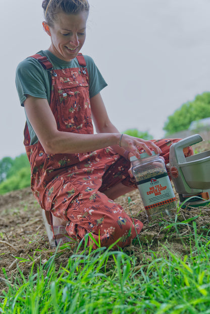 No Till Cover Crop Mix seeds bottle with Tin Shed Seed Co label held by gardener in red overalls on Tampa Home & Garden Store