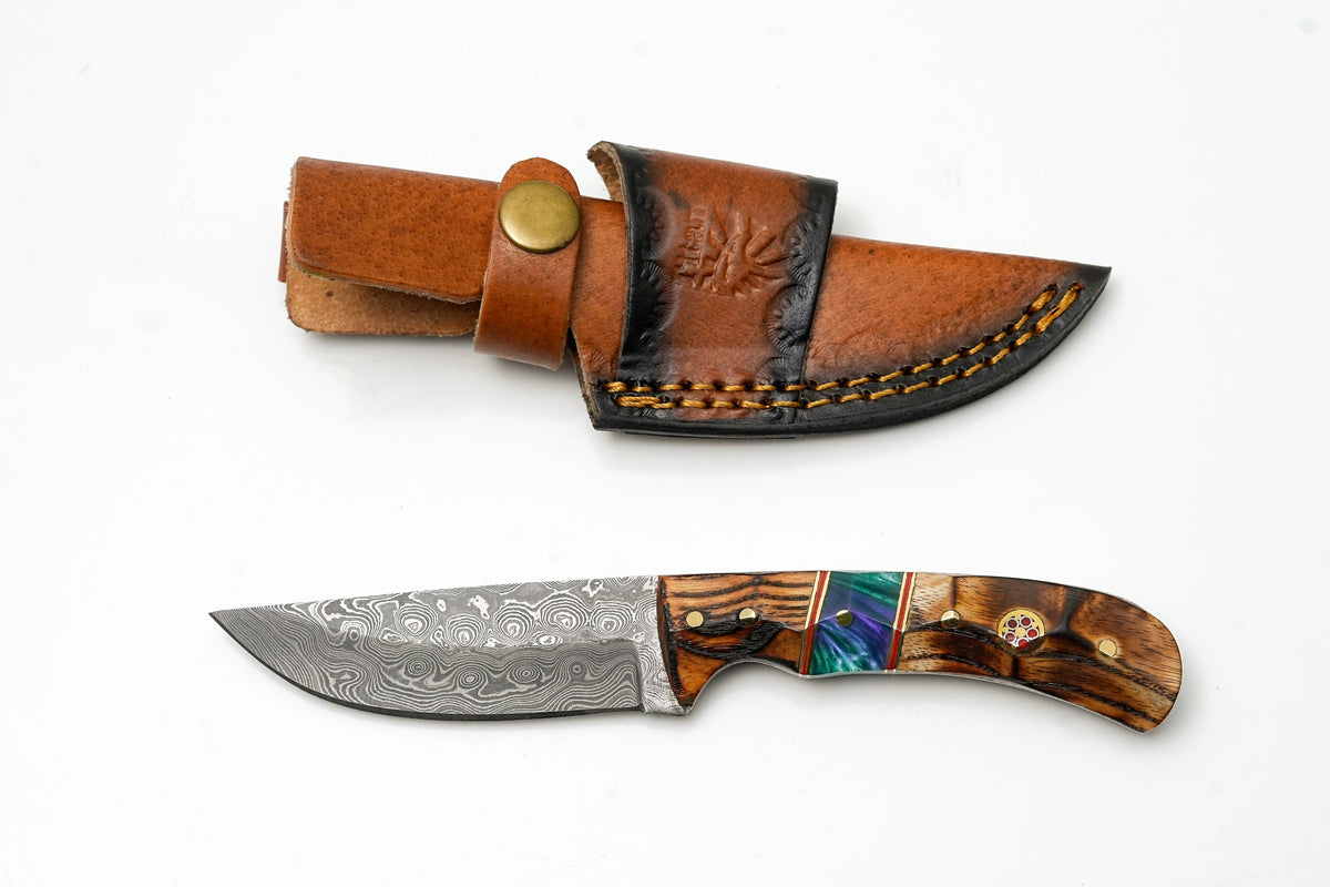 Hand-Forged Damascus Skinner knife with torched wood & resin handle in brown leather sheath; second Damascus blade with colorful inlay visible on Tampa Home & Garden Store