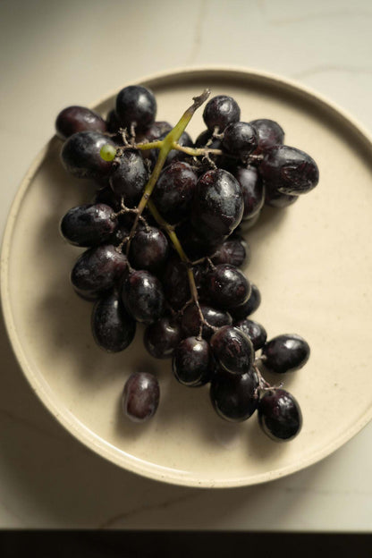 Handmade stoneware plate white speckled with a cluster of dark purple grapes on Tampa Home & Garden Store