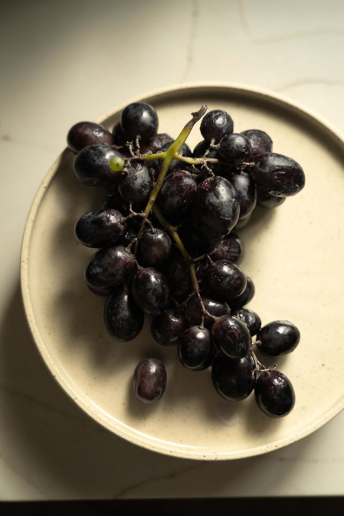 Handmade stoneware plate white with speckles, cluster of dark grapes on it on Tampa Home & Garden Store