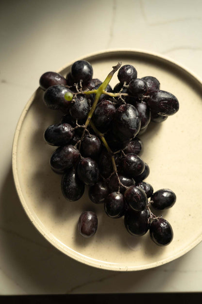 Handmade stoneware plate white with speckles, cluster of dark grapes on it on Tampa Home & Garden Store