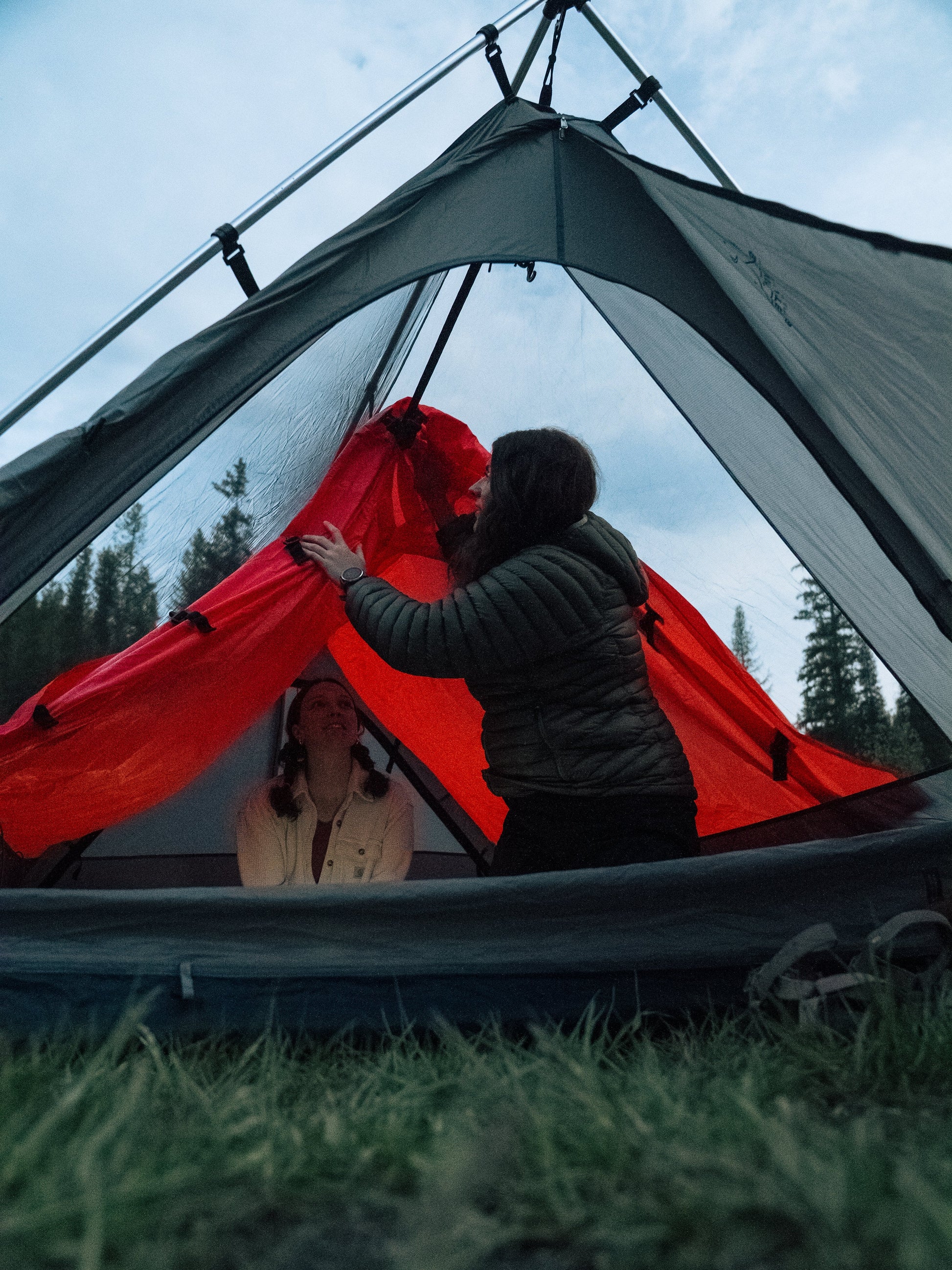 Sky View XL Tent with red inner tent being pitched by two people under a metal frame on Tampa Home & Garden Store