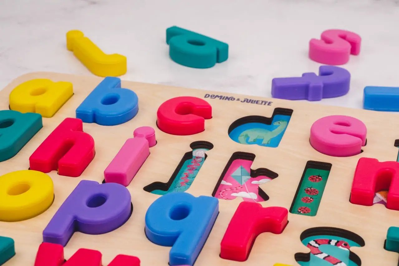 Find & Fit Puzzle letters by Domino & Juliette, colorful plastic alphabet on a wooden board with cutouts and a dinosaur image on Tampa Home & Garden Store
