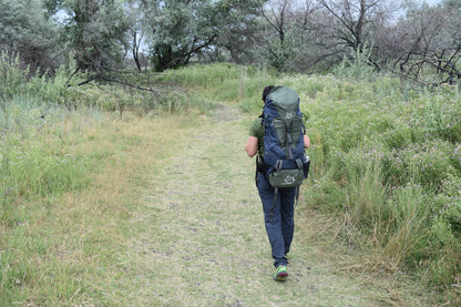 65 Liter River Country Gear backpacking pack in blue with green lid on a hiker on trail on Tampa Home & Garden Store